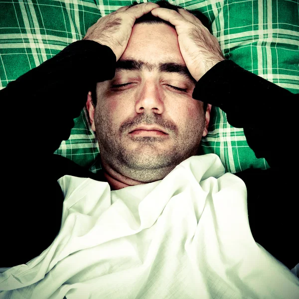 Стресс или психически неуравновешенный мужчина лежит в постели — стоковое фото