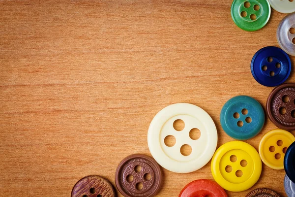 Botones de costura coloridos sobre un fondo de madera — Foto de Stock