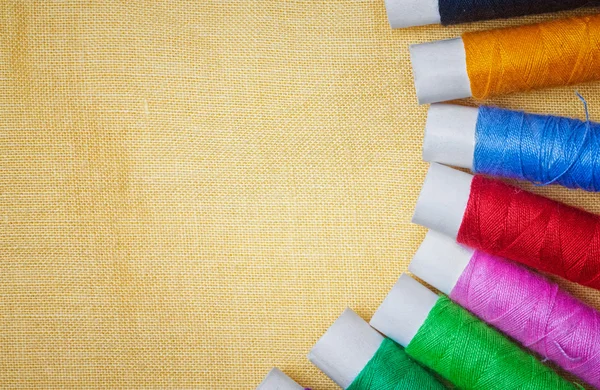 Bobine di filo per cucire su uno sfondo di tessuto giallo — Foto Stock