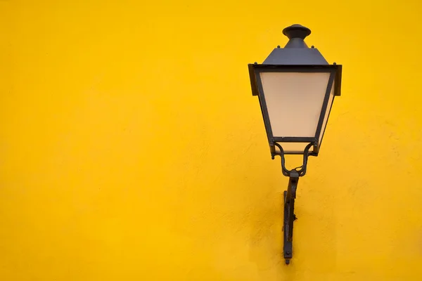 Lâmpada de rua velha em uma parede amarela — Fotografia de Stock