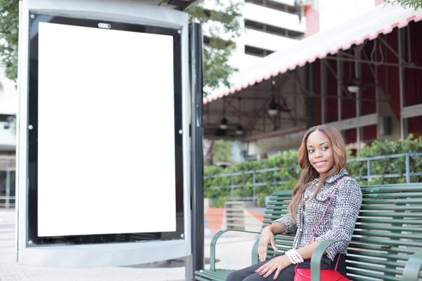 Женщина сидит на автобусной остановке скамейке — стоковое фото