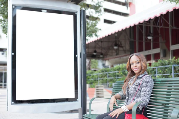 Woman sitting at a bus stop bench — Stock Photo, Image