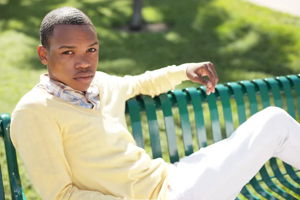 Νεαρός Μαύρος άνδρας κάθεται σε ένα παγκάκι — Φωτογραφία Αρχείου