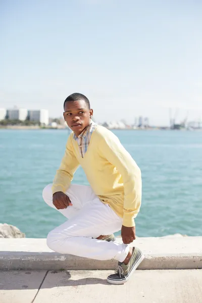 Homem agachando em roupas da moda — Fotografia de Stock