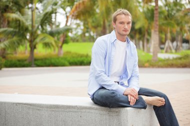 Smart casual man sitting in the park clipart