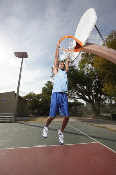 Basketball player hanging from the hoop — Stock Photo, Image