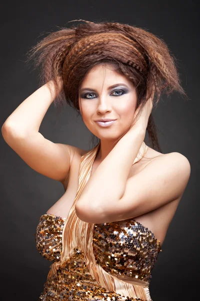 Жінка в золотій сукні грає з волоссям — стокове фото