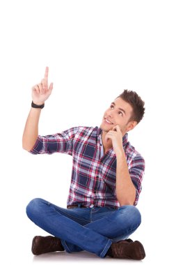 Seated young casual man pointing at something up
