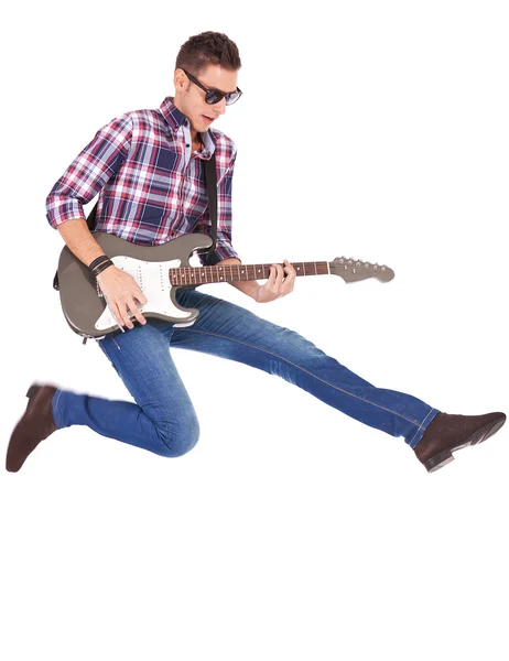Guitarist playing an electric guitar while jumping — Stock Photo, Image