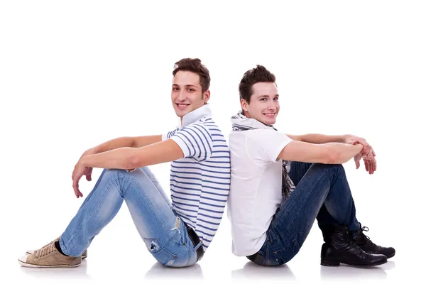 Due giovani uomini casual seduti schiena a schiena — Foto Stock