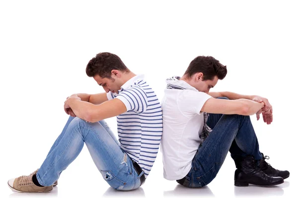 Due uomini tristi seduti schiena contro schiena — Foto Stock