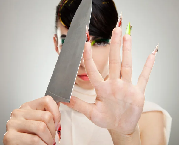 Woman sharpening her nails with knife — Stock Photo, Image