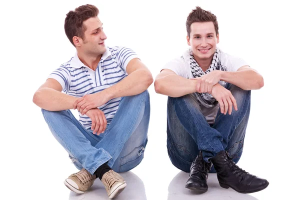 Two casual men sitting on a white background Royalty Free Stock Images