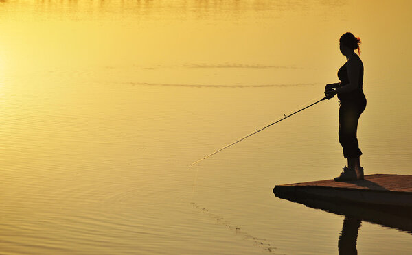Silhouette of a fishing woman at sunset