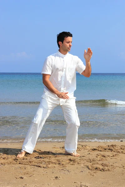 Hombre guapo practicando tailandés chi en la playa — Foto de Stock