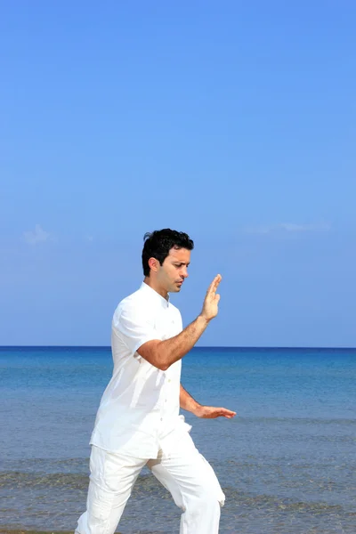 Pohledný muž cvičit Tai-chi na pláži — Stock fotografie