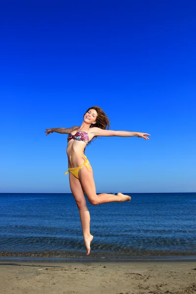 Mooi meisje sierlijk springen op het strand — Stockfoto