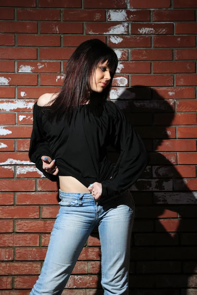Modeporträt einer jungen Frau mit Ziegelwand — Stockfoto
