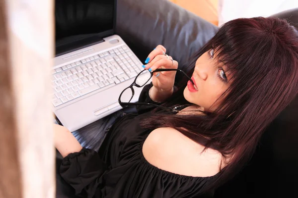 Jovem mulher no sofá e trabalhando no laptop — Fotografia de Stock