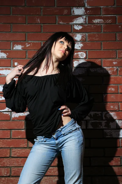 Modeporträt einer jungen Frau mit Ziegelwand — Stockfoto