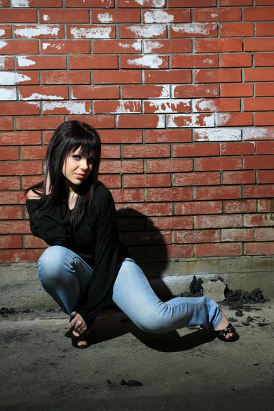 Módní portrét mladé ženy s cihlovou zeď — Stock fotografie