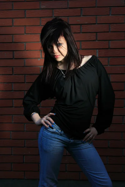 Módní portrét mladé ženy s cihlovou zeď — Stock fotografie