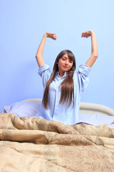 Kvinna sitter i sängen och stretch — Stockfoto