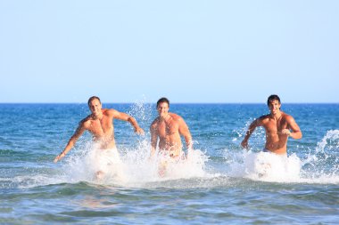 Üç genç adam sahilde rahatlatıcı