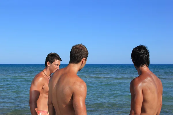 Τρεις νεαροί άνδρες χαλαρώνοντας στην παραλία — Φωτογραφία Αρχείου