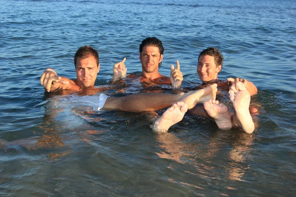 Trois jeunes hommes se relaxant sur la plage — Photo