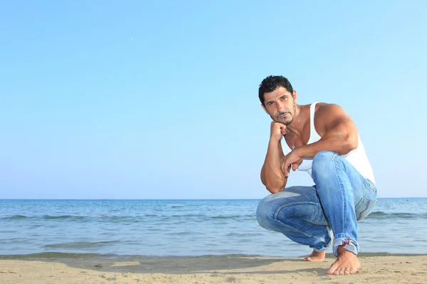 Красивый мужчина в джинсах у моря — стоковое фото