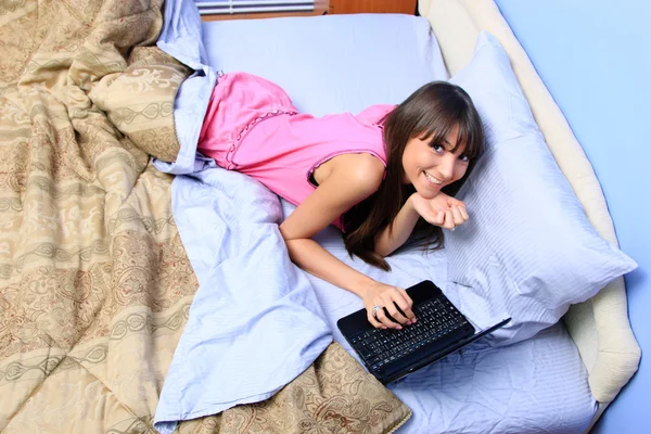 十几岁的女孩在床上看她的便携式计算机 — 图库照片