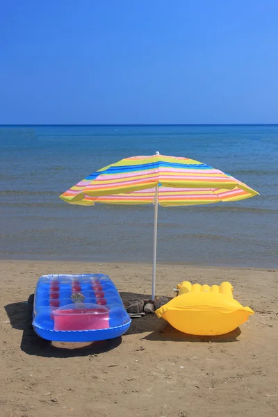 Luftmadrass och parasoll på stranden — Stockfoto