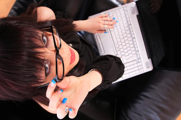 Young woman on couch and working on laptop Stock Picture