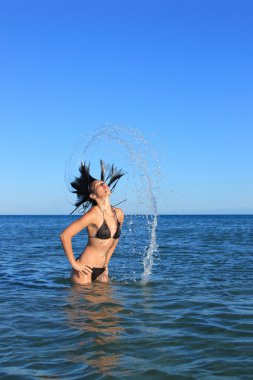 Cute girl on the beach splashing out of the water