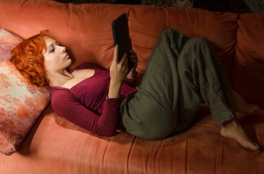 Curly woman on a sofa with ebook clipart