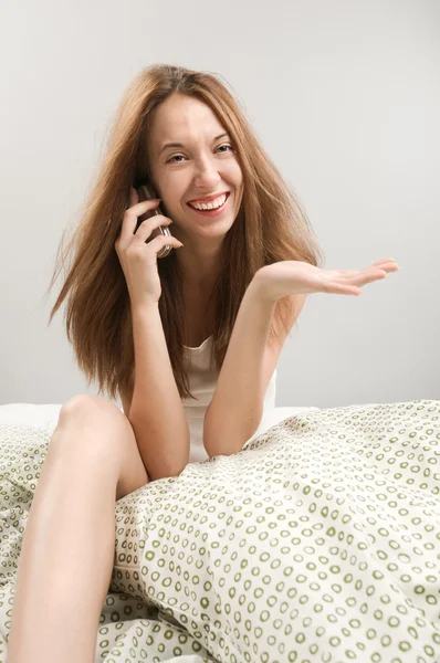 Женщина в постели с телефоном — стоковое фото