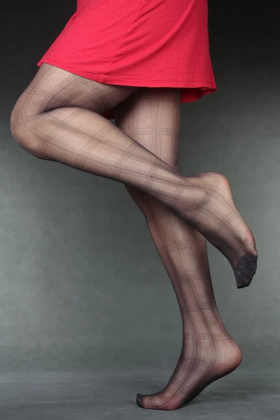 Vacker kvinna benen bär strumpbyxor & röd klänning över grå — Stockfoto