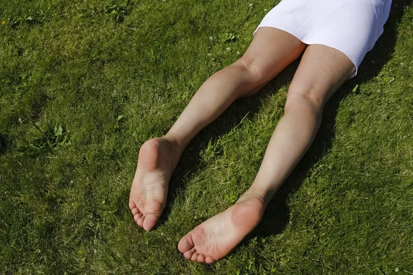 女性双腿放松草草坪与鲜花 — 图库照片