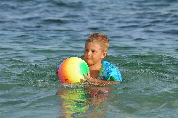 Мальчик на пляже играет с мячом — стоковое фото