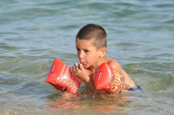 Хлопчик у морі вчиться плавати — стокове фото