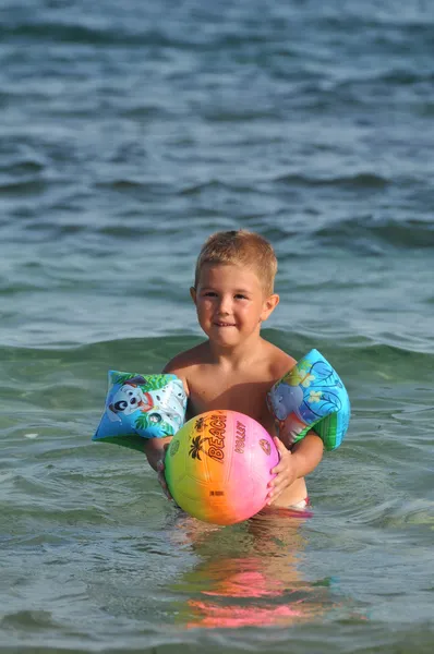 Chlapec na pláži hraje s míčem — Stock fotografie