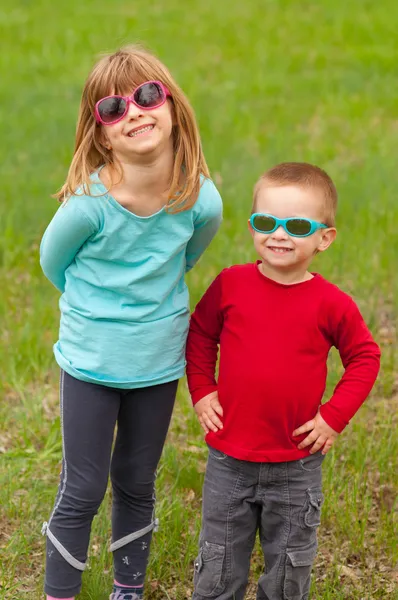 Брат и сестра позируют на улице в солнечных очках в прекрасный весенний день — стоковое фото