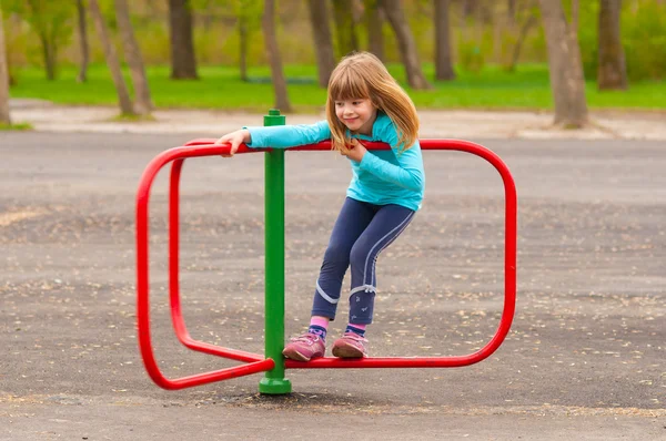 Söt liten flicka som leker på lekplatsen på vackra vårdag — Stockfoto