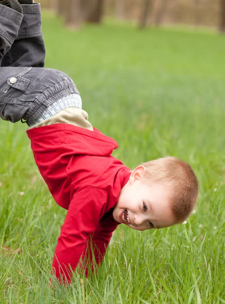 Menino feliz brincando na grama no belo dia de primavera — Fotografia de Stock