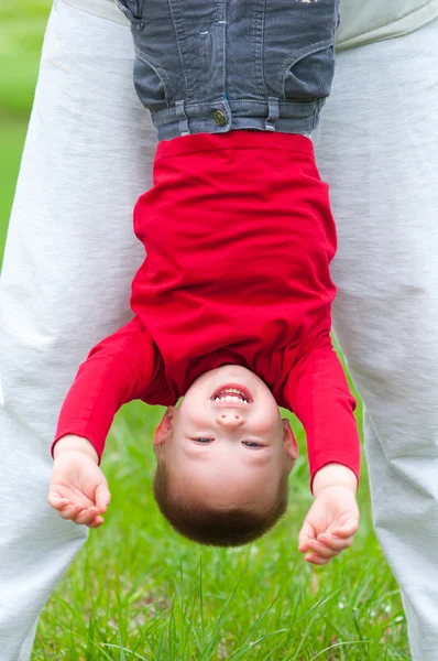 Cute happy boy hanging upside down on beautiful spring day — Stock Photo, Image
