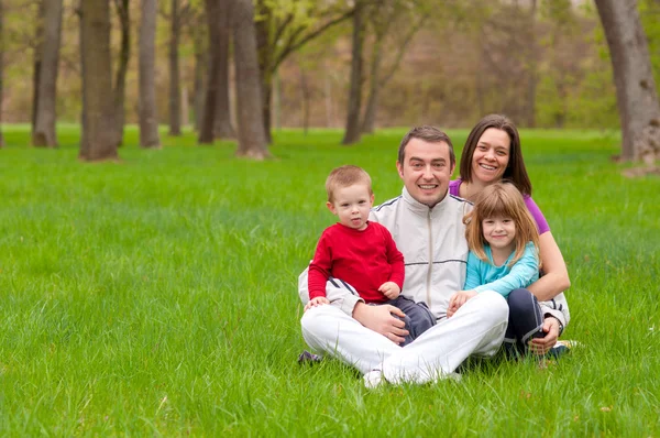 Młody szczęśliwą rodzinę, zabawy z natury na dzień wiosny piękny — Zdjęcie stockowe