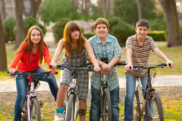 Quatre amis adolescents heureux à vélo dans le parc — Photo