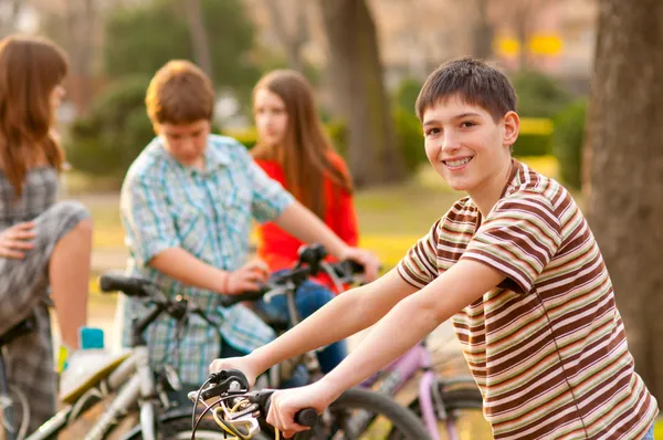 Happy teenage boy spending time with his friends riding bicycles — Stock Photo, Image
