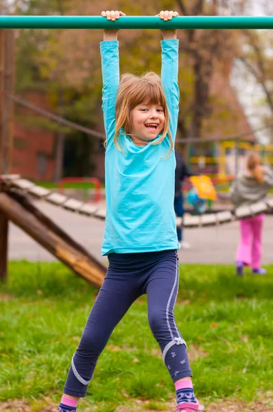 Bonita menina brincando no playground no dia nublado da primavera — Fotografia de Stock